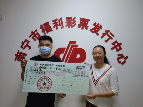 图1：南宁市福彩中心工作人员为王先生（左）颁奖