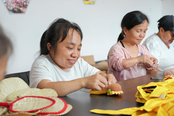 （图为：徐礼珍在制作福彩定制手工向日葵太阳帽）