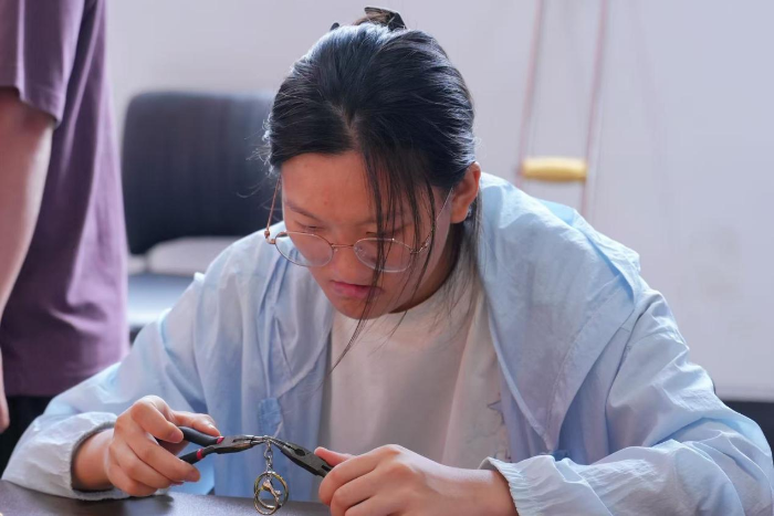 （图为：田鑫正在制作福彩定制手工向日葵太阳帽扣环）